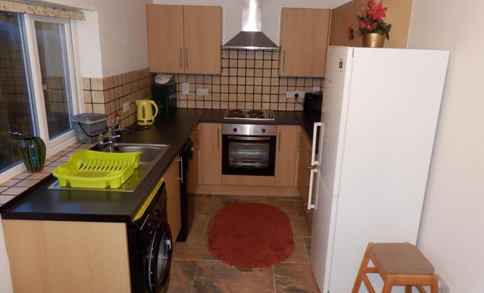 hawthorn kitchen/dining area. Shows full size fridge freezer, oven, hob, washing machine and dishwasher. Table and chairs are situation at the bottom